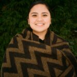 A photo of a filipino woman with her hair parted and tied back. She is wearing a scarf with a zigzag pattern.